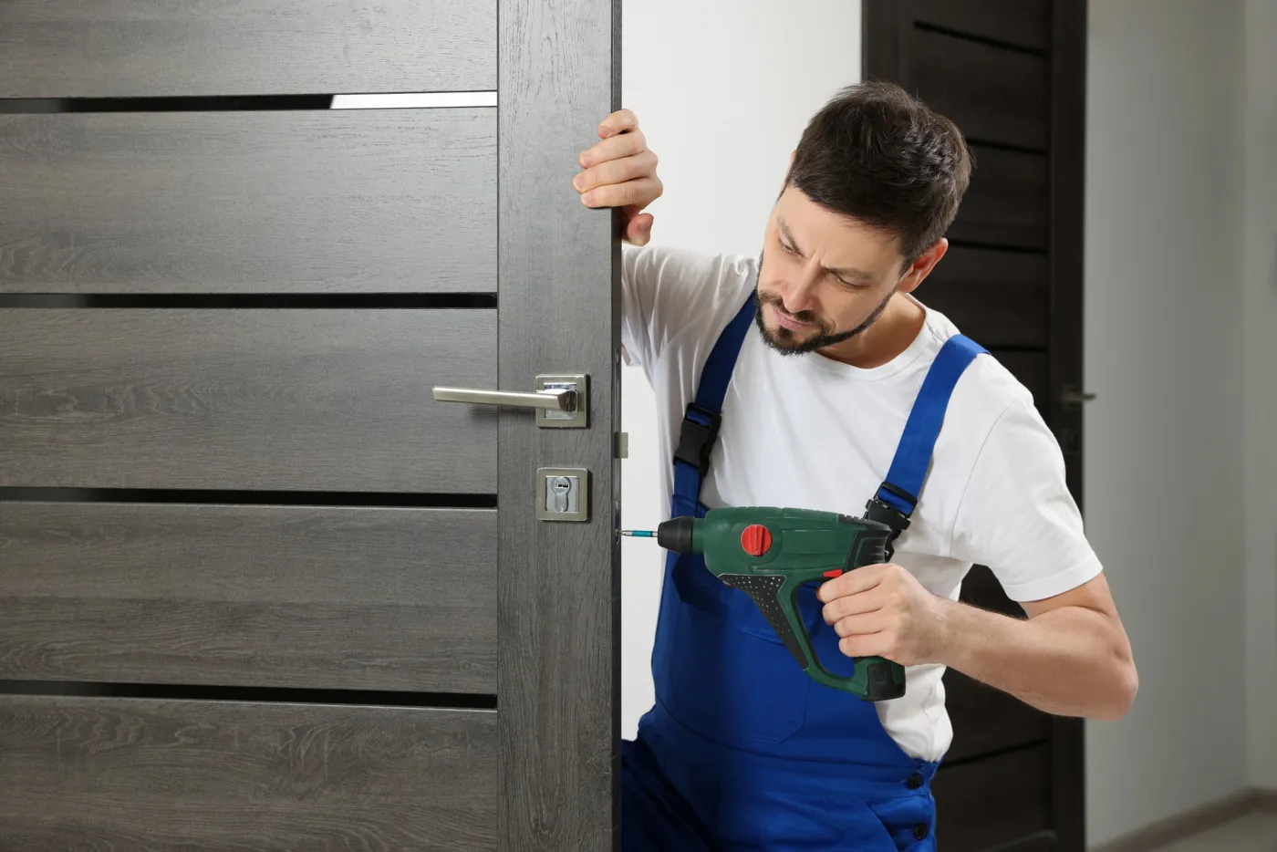 Artisan serrurier posant une poignée et une serrure sur une porte de maison à Beynes (78650)